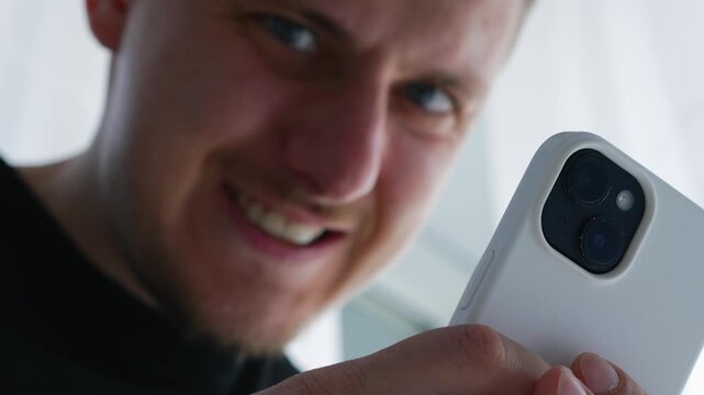 A smiling and happy man takes a photo with a smartphone camera with a flash and enjoys a beautiful shot.
Content creator creates a photo using a phone and a bright flash