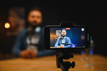 Content creator recording video blog with smartphone and microphone