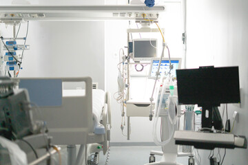 Empty hospital bed with monitoring equipment stands ready in intensive care unit