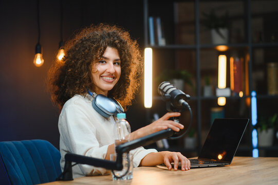Young woman recording a podcast using a professional microphone and laptop