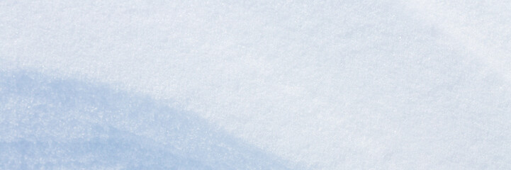Beautiful winter background with snowy ground. Natural snow texture. Wind sculpted patterns on snow surface. Wide panoramic texture for background and design. Closeup top view with copy space.