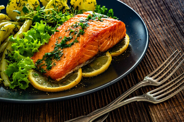 Fried salmon steak with yellow beans and boiled potatoes on wooden table	