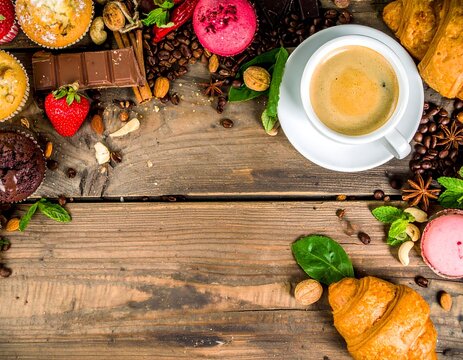 Coffee cup with assorted pastries and sweets on rustic wood