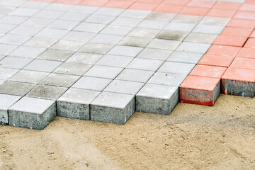 Laying paving slabs on sand bed during outdoor construction illustrating installation process. Paving slab installation outdoors with construction work on sand bed base