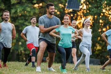 Group of people participating in outdoor fitness class during sunset in a park
