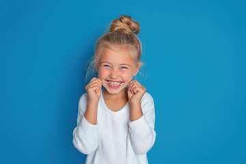 Fototapeta premium Happy girl flossing teeth, promoting healthy dental hygiene on vibrant blue background