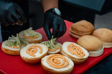 assembling a burger by a chef. bun with sauce and vegetables close-up