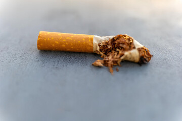 Cigarette stub abandoned on a concrete surface at dusk, capturing fleeting moments of urban life and its residues