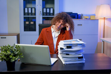 Tired young woman working late at the office, looking sleepy, using smartphone, wanting to relax,...