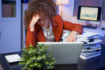 Tired young woman working late at the office, looking sleepy, using smartphone, wanting to relax,...