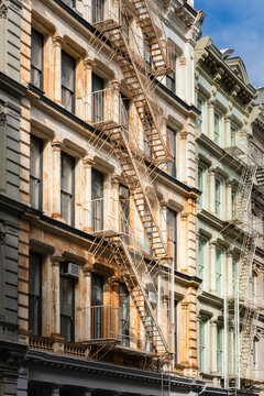 Weathered cast-iron facade with rust on architectural columns and fire escapes. Classic SoHo Cast Iron Historic District architecture in Manhattan, New York City