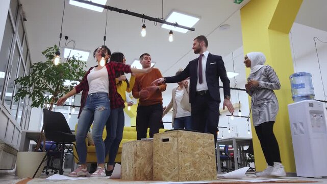 A Diverse Group of Enthusiastic Young Business Professionals Celebrates a Major Victory and Success with an Energetic and Happy Dance Party in their Modern Office Environment.