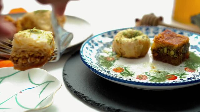 A woman serving baklava from the table onto a small plate with a fork