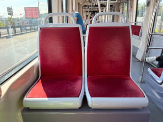 Red upholstered tram seats in urban vehicle. Public transport, passenger service, and city mobility...