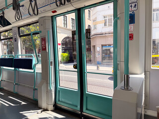 Tram doors and seating area in sunlight. Urban commuting, modern infrastructure, and daily travel.