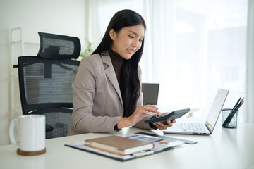Asian businesswoman using a calculator while working at her desk.