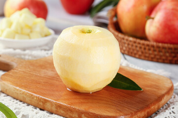 Peeled Fresh Apple on Wooden Board with Red Apples in Basket Background