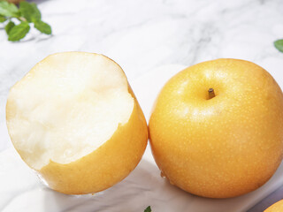 Fresh Asian Pears Cut and Whole on White Marble Background with Mint Leaves