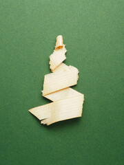 Christmas tree shaped wood shavings on a green paper background, plastic-free holiday greetings...