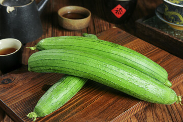 Freshly Picked Green Luffa Gourds on Wooden Board - Traditional Asian Vegetables