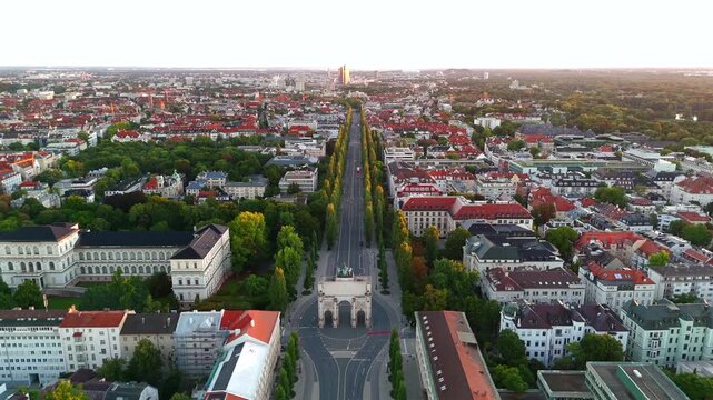 Drone footage of Siegestor in Munich, capturing historic triumphal arch, Bavarian landmarks, Maxvorstadt and Schwabing districts at golden hour, ideal for cinematic cityscape and travel videos