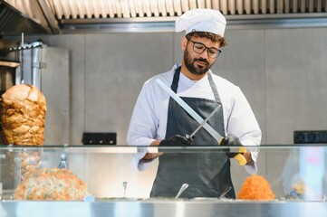 Chef sharpening knife preparing shawarma or kebab in restaurant kitchen