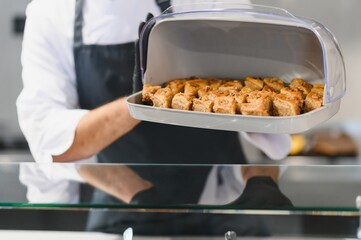 Chef holding tray of baklava in restaurant kitchen