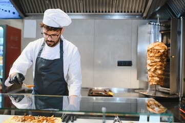 Chef adding spices to shawarma ingredients in a modern kitchen