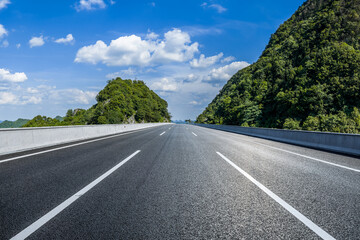 Straight asphalt highway road passing through beautiful green mountain natural landscape on a sunny...