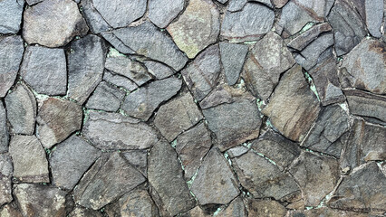 Close-up of an irregular natural stone wall with rough textures and visible mortar lines