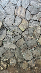 Close-up of an irregular natural stone wall with rough textures and visible mortar lines