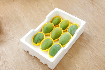 Fresh Green Mangoes in White Foam Box on Wooden Table - Panzhihua Fruit Packaging