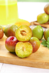 Fresh Sichuan Plums Cut in Half Showing Yellow Flesh on Wooden Board