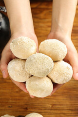 Fresh Fluffy Golden Bread Rolls Held in Cupped Hands on Wooden Background