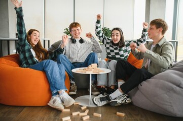 Happy friends playing exciting board game at home