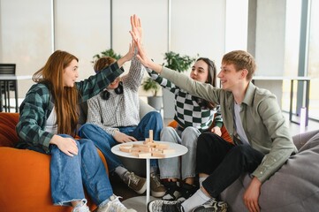 Happy students giving high five celebrating success playing board game