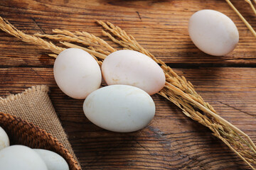 Large Fresh Duck Eggs on Rustic Wooden Farmhouse Table with Wheat Stalks