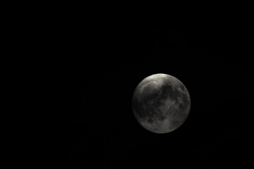 Small clouds obscured the full moon in the sky