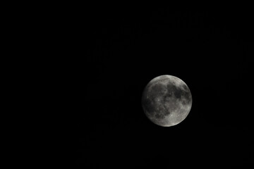 Small clouds obscured the full moon in the sky