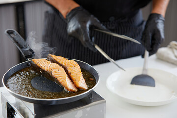 chef cooking salmon steaks in the kitchen