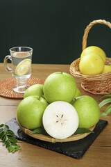 Fresh Green Apples on Wooden Table with Wicker Basket and Lemon Water Glass