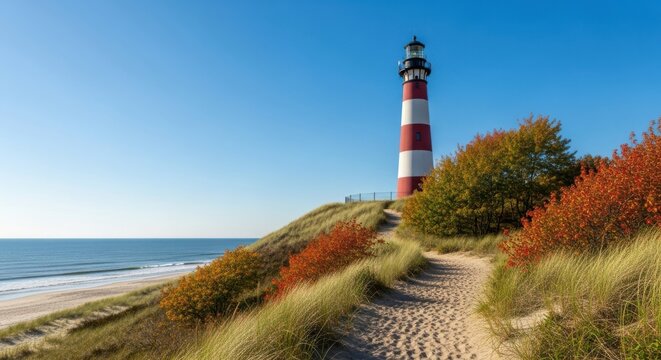 Red and white striped lighthouse on a grassy dune overlooking the ocean