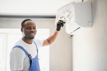 Happy Young African Male Technician Repairing Air Conditioner