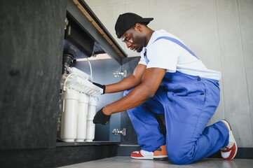 Technician installing reverse osmosis equipment under the sink