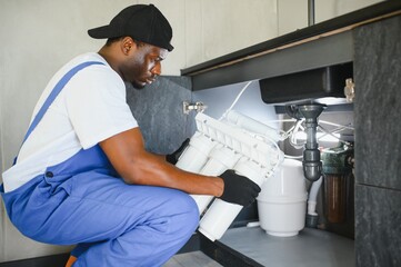 African american plumber change the water filter.