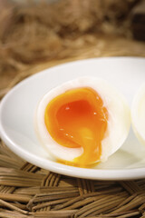 Fresh Farmhouse Egg with Golden Yolk in White Bowl on Rustic Wicker Background