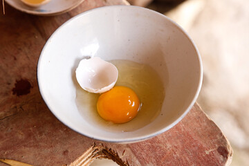 Fresh Farm Egg Cracked in Bowl Ready for Cooking on Rustic Wooden Board