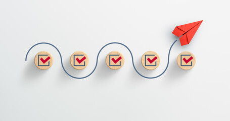 Red paper plane and wooden cubes with red marking on checklist box, Checklist concept
