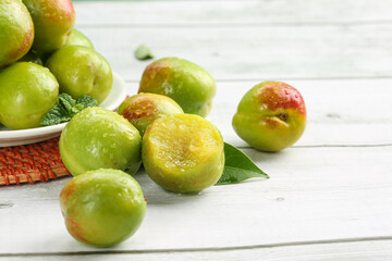 Fresh Green-Skinned Apricots and Large Pear Display on White Wood Background