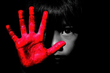Child's silhouette holding a red-painted hand up in protest with copy space.